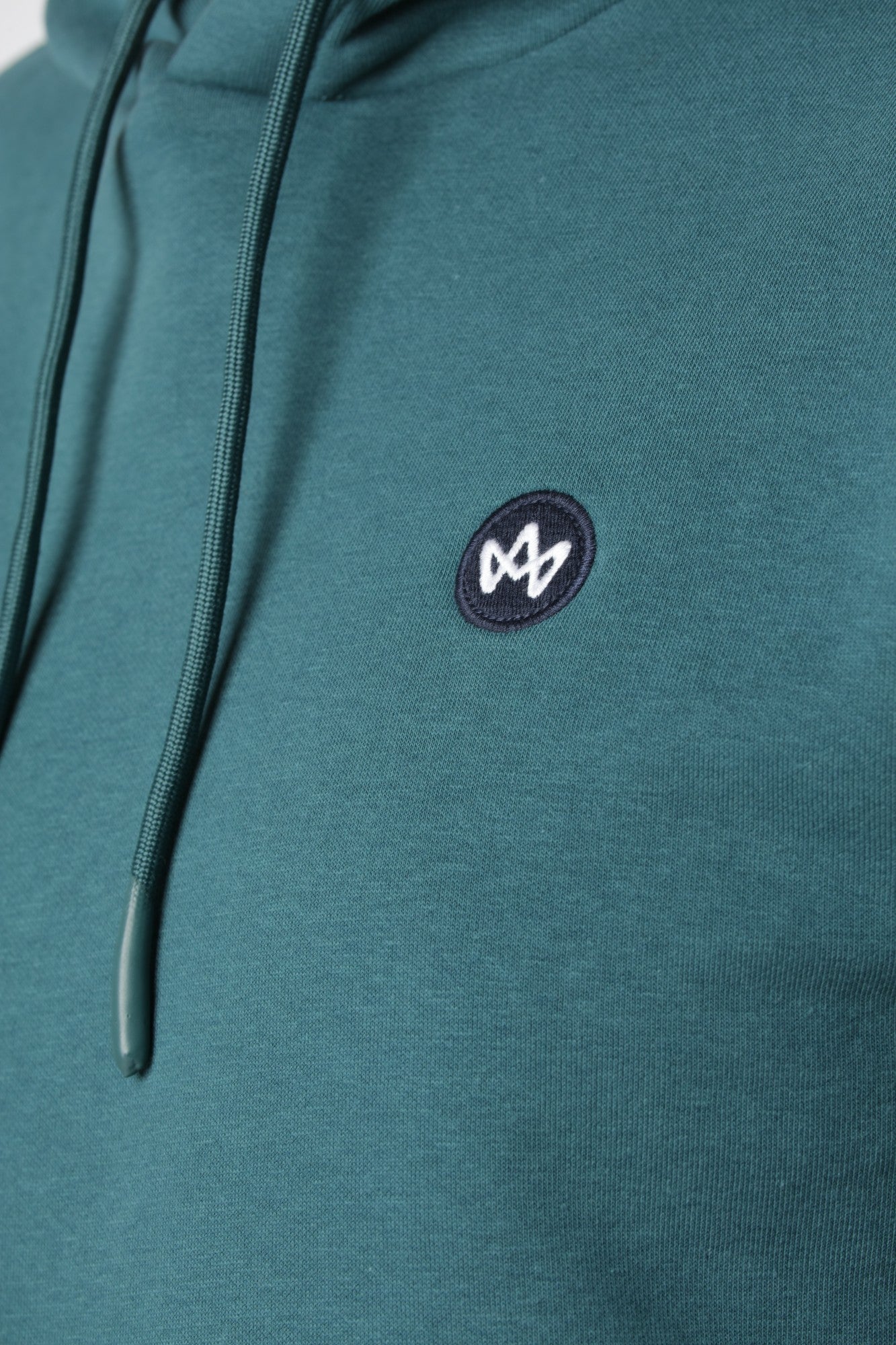 Kronstadt hoodie i farven Mediterranea med lille farverigt broderi på brystet som detalje