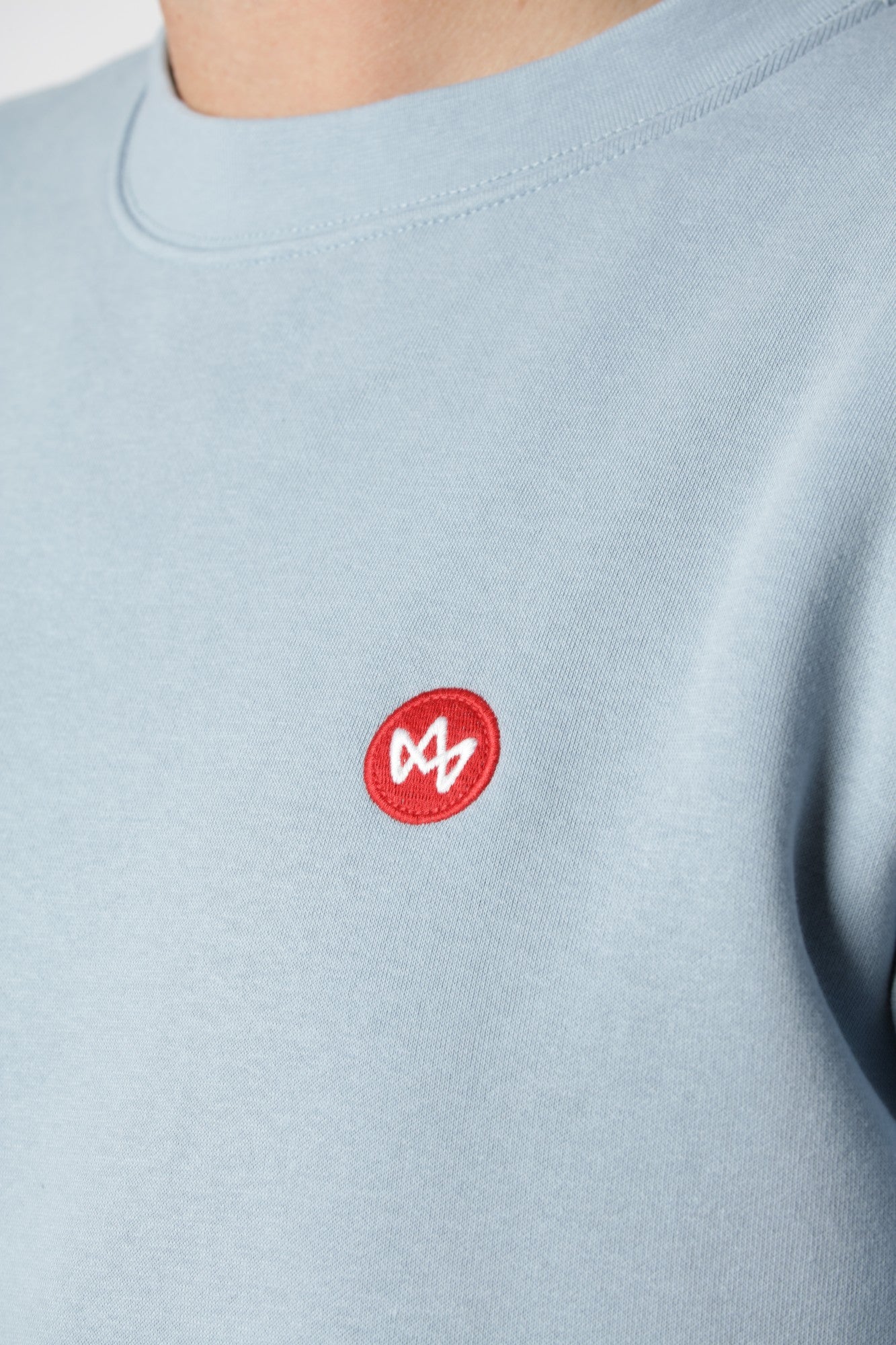 Kronstadt sweatshirt i Ashley Blue med lille farverigt broderi på brystet som subtil kontrast til den lyse tone.