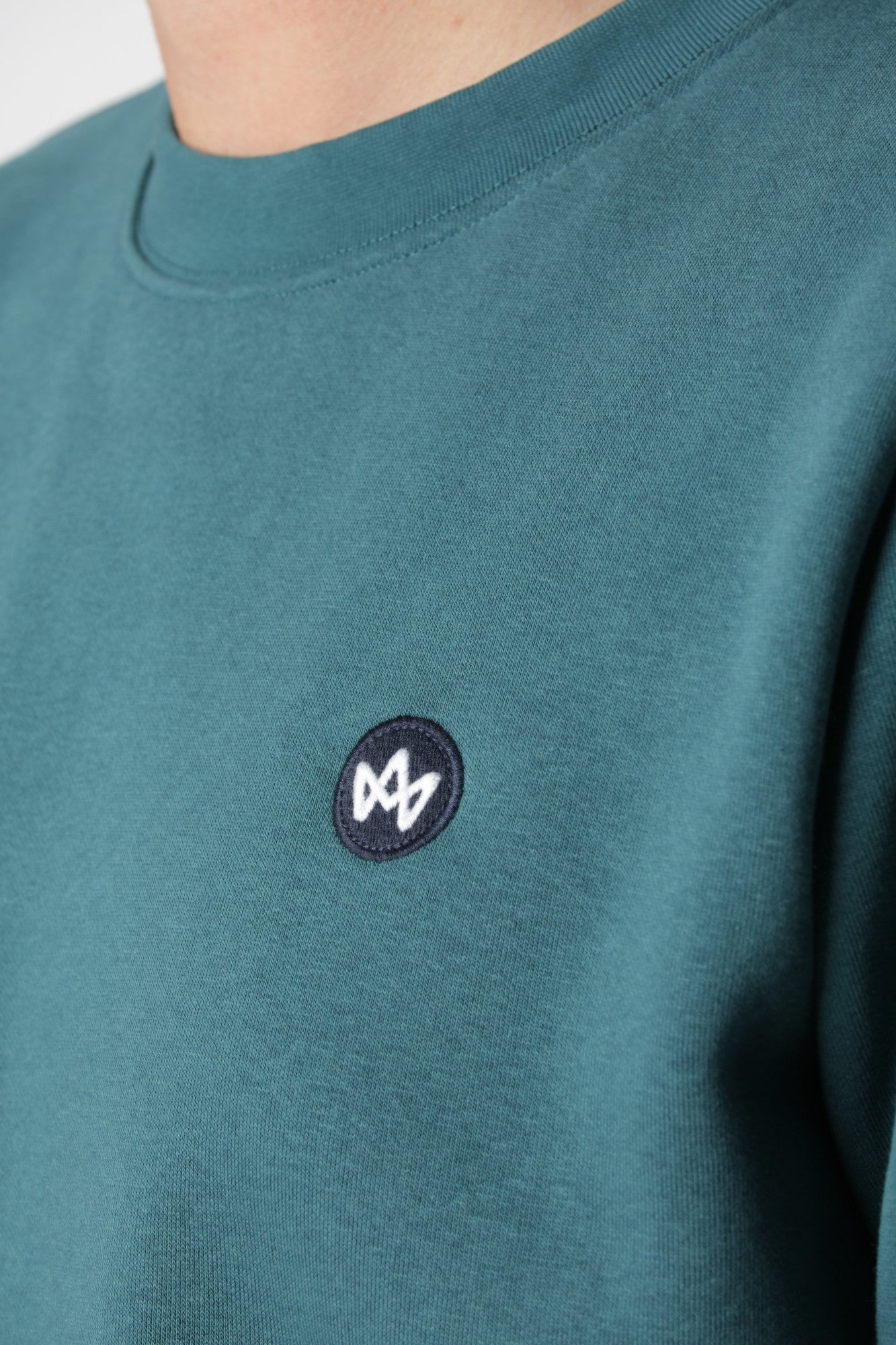Kronstadt sweatshirt i Mediterranea med lille farverigt broderi på brystet som subtil kontrast til blågrøn farve.
